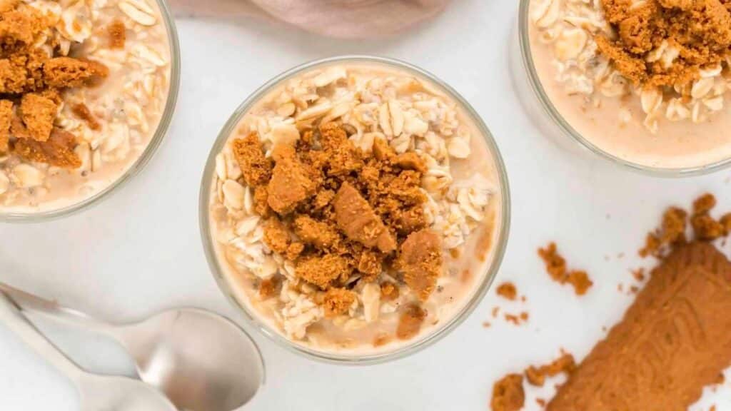 Biscoff Overnight Oats in jars topped with crushed cookies on a light background.
