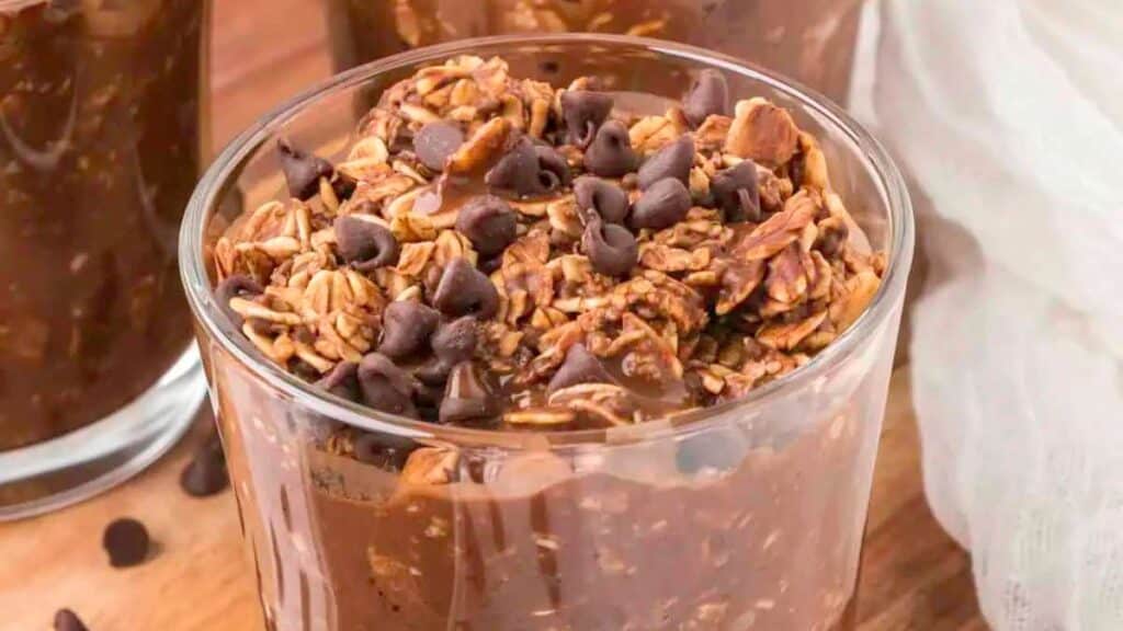 Brownie Batter Overnight Oats topped with chocolate chips on a wood background. 