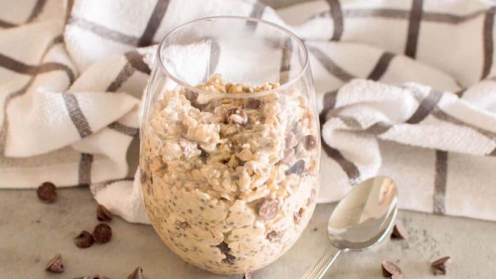 Cookie dough overnight oats in a glass with a plaid towel in the background.