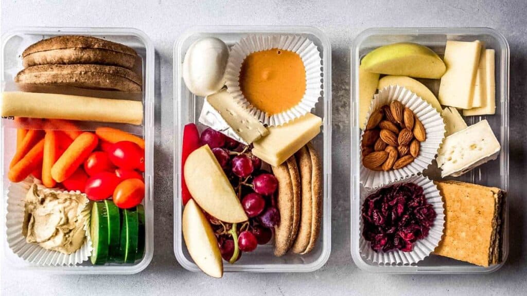 Three containers full f food on a counter.