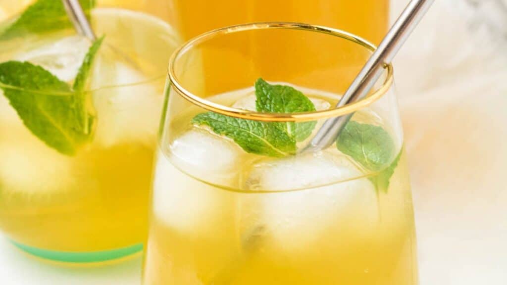 A glass of Green Tea Lemonade with a metal straw in it.