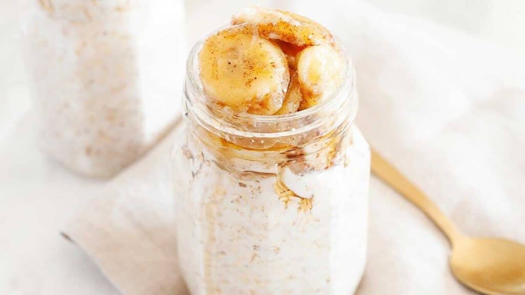 Banana foster overnight oats with banana slices on top on a light background.
