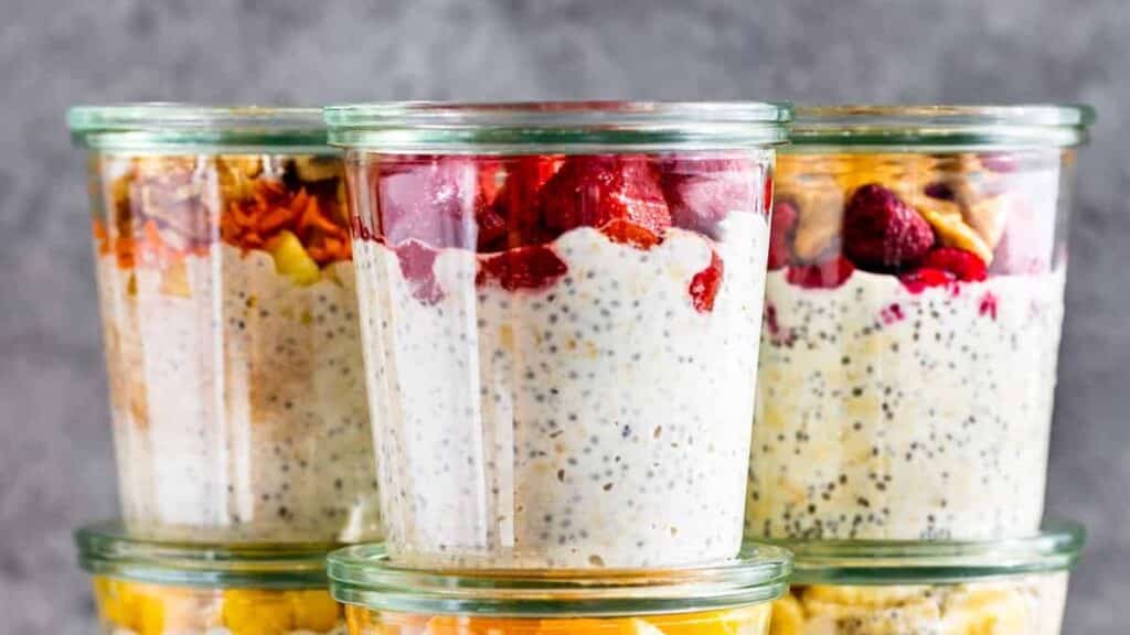 Different overnight oats flavors stacked up in jars on a grey background. 