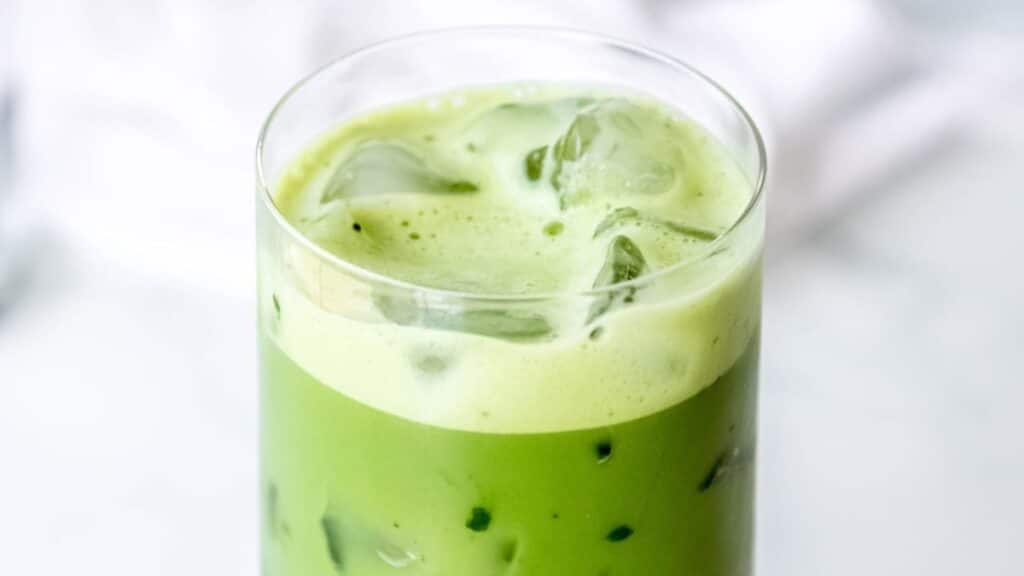 A glass of Iced Matcha Latte with ice in it.