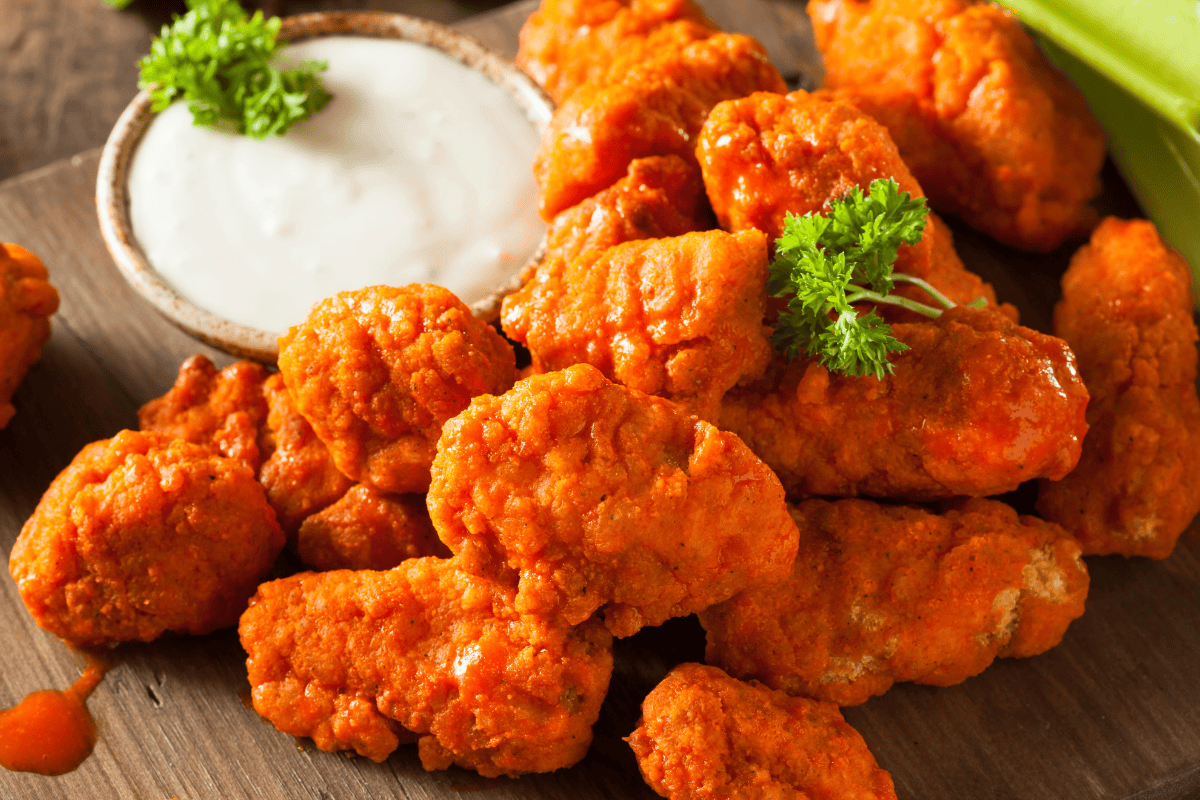 Buffalo chicken nuggets with ranch dipping sauce on brown background.