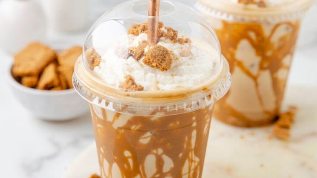 Cookie butter latte with caramel drizzle in a plastic cup.