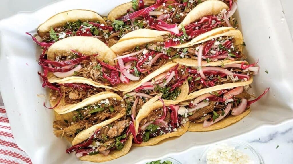 Several pork street tacos on a white background.