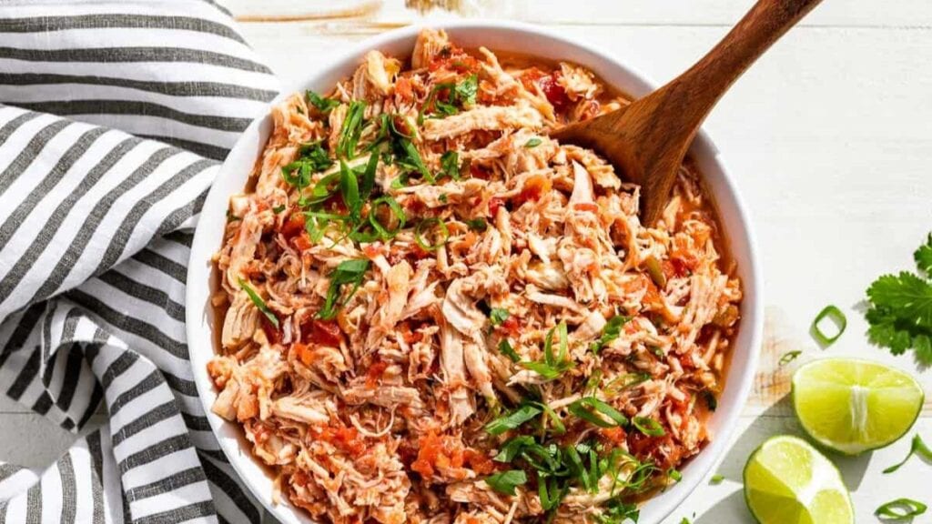 Salsa chicken in a white bowl with wood spoon.