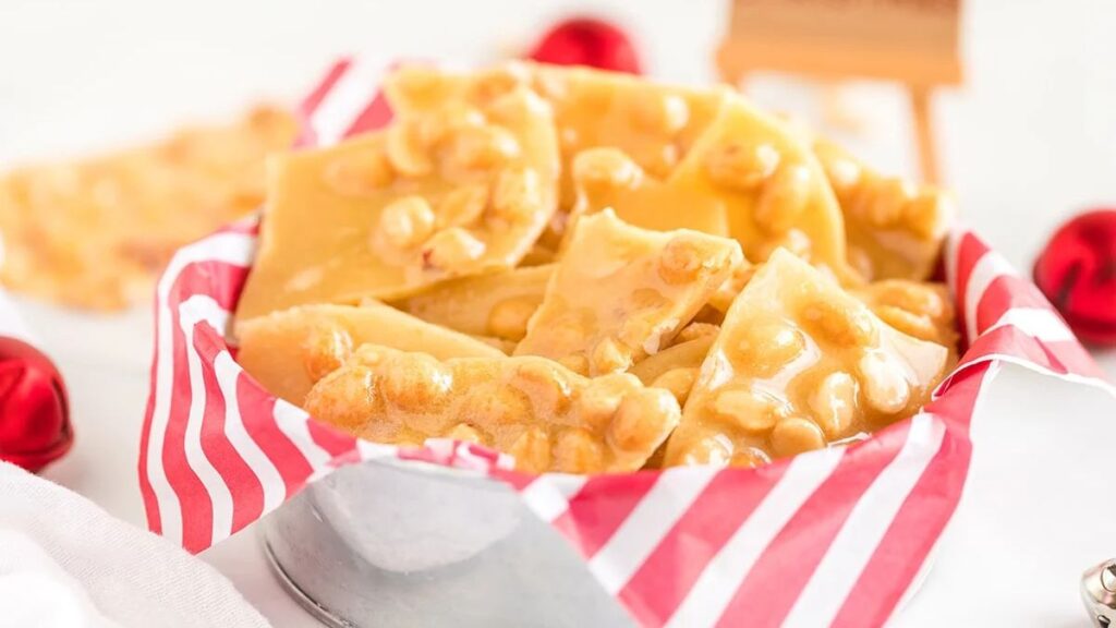 Peanut brittle in a bowl with red and white tissue paper.