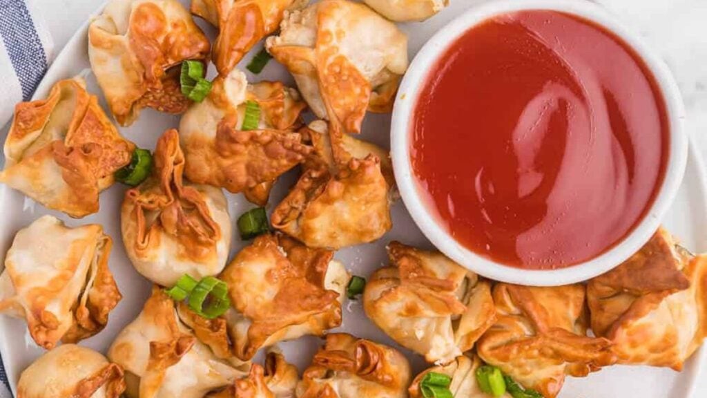 Rangoon on a plate next to dipping sauce.