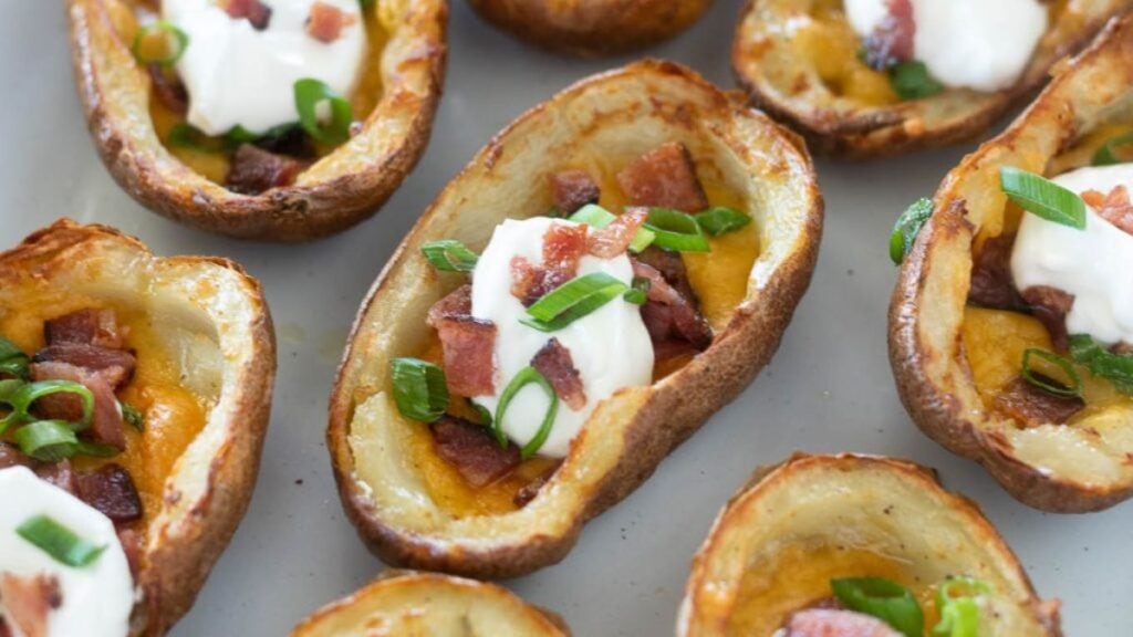Potato skins filled with sour cream, cheese, and bacon on a pan.