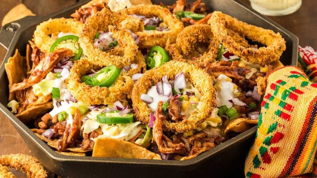Nachos topped with BBQ meat, onion rings, and other ingredients.