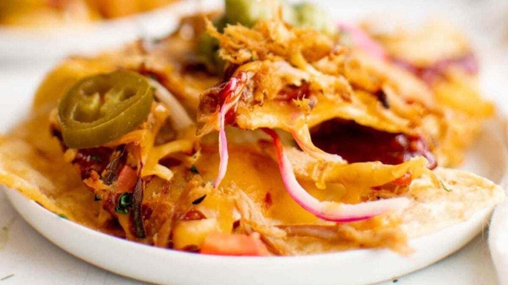 Pulled pork nachos on white plate.