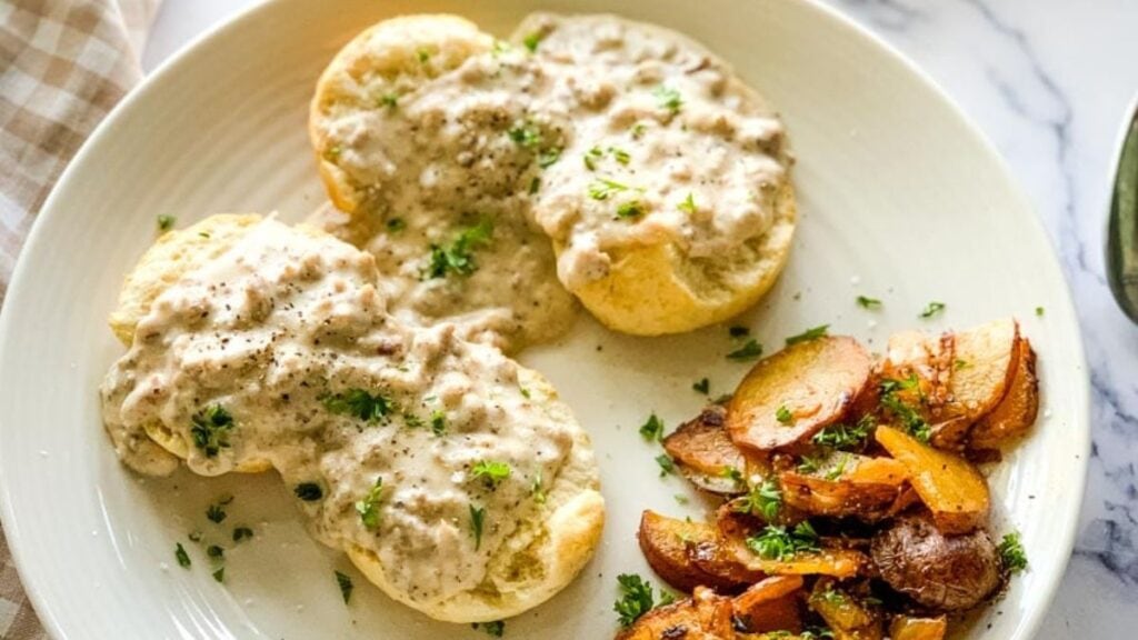 Biscuits and gravy on a plate with potatoes.