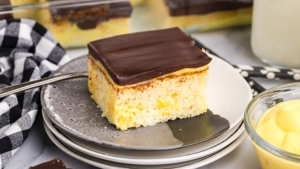 A piece of boston cream poke cake on a plate.