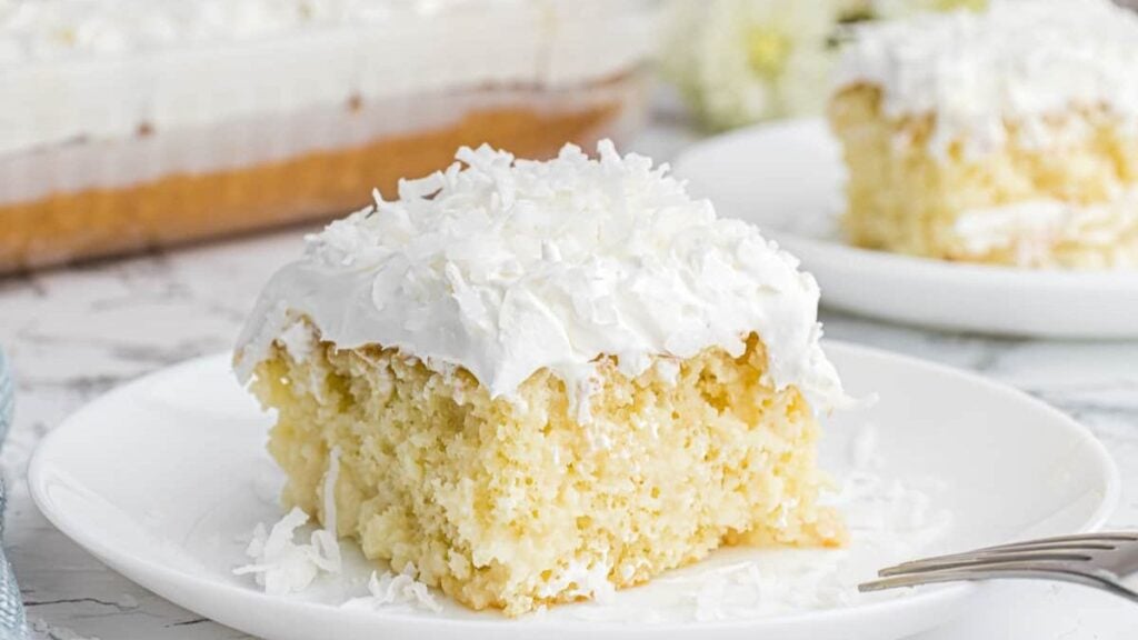 Piece of coconut flavored cake on a white plate.