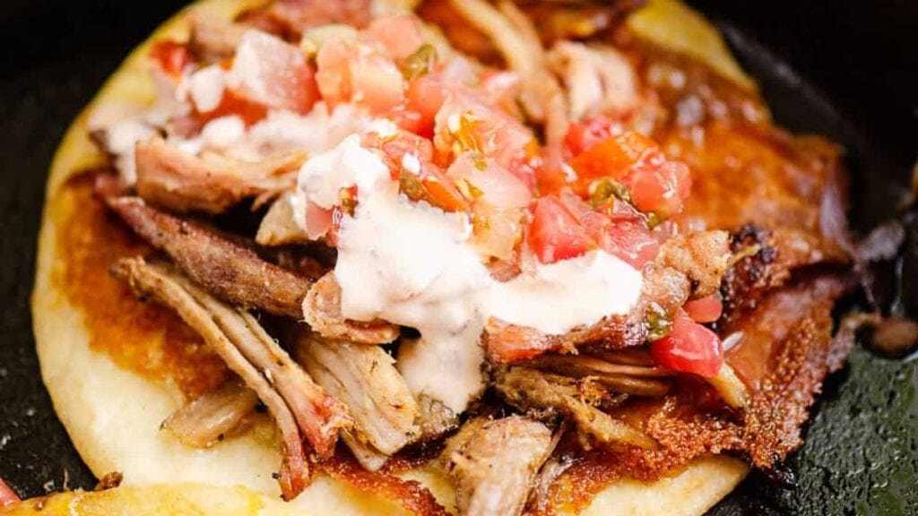Taco with pork, tomatoes and creamy sauce.