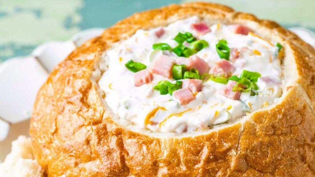 A creamy dip in a bread bowl for serving.