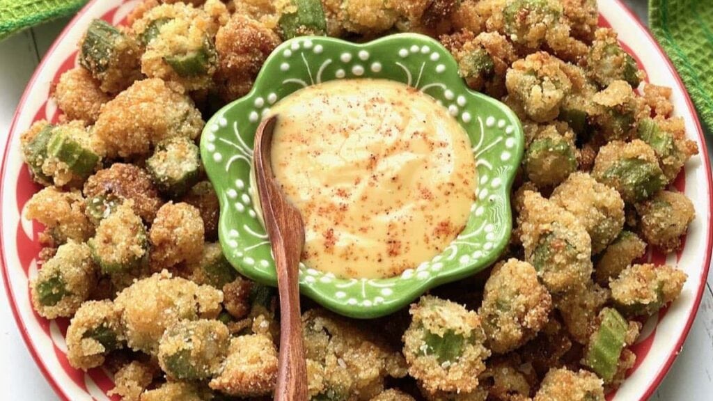 Fried okra on a plate around a bowl of dip.