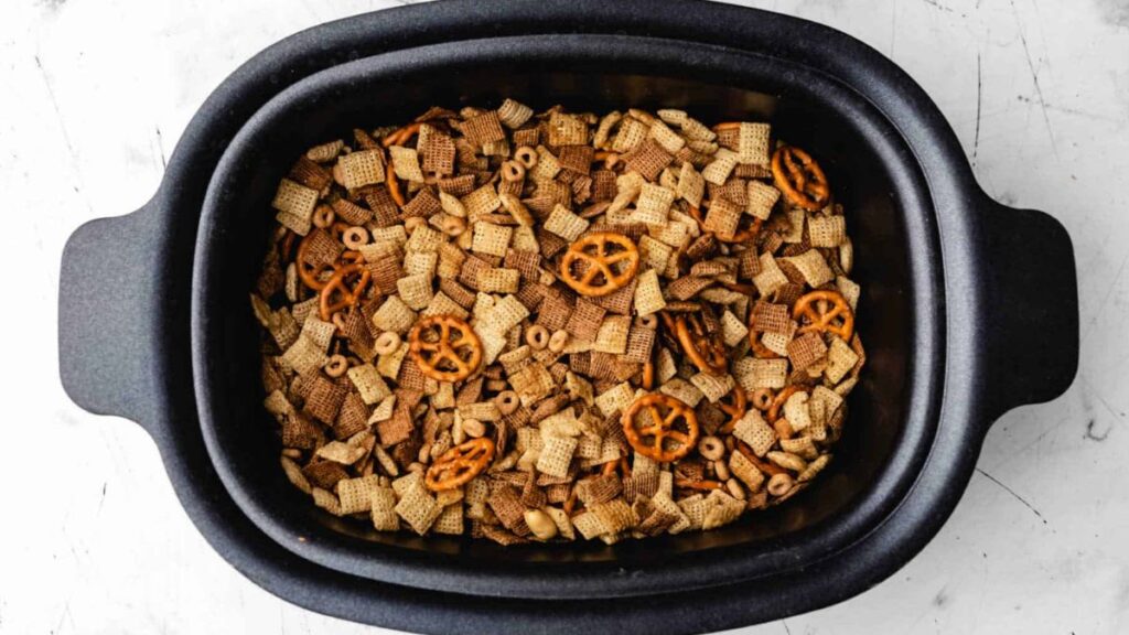 Slow cooked chex mix in a black pot.