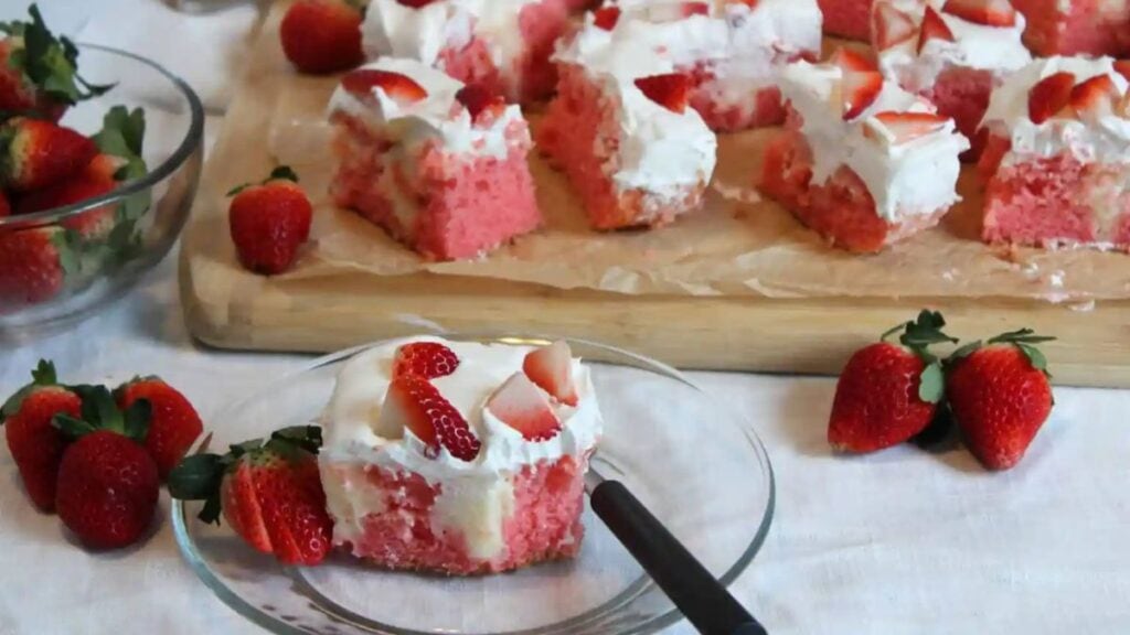 Pieces of strawberry cheesecake poke cake.