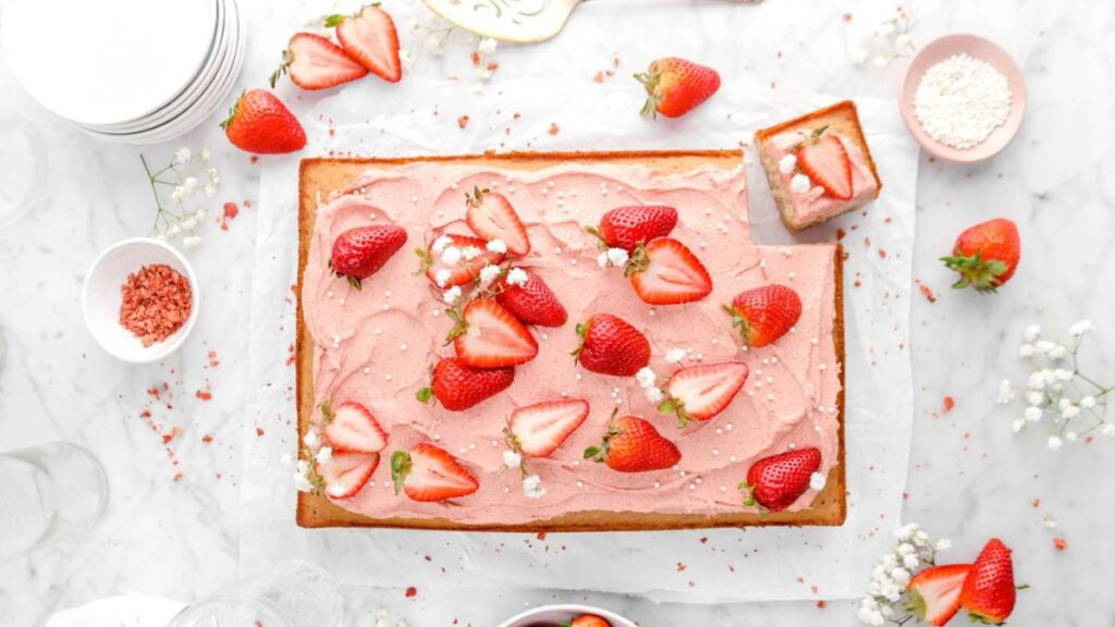 Strawberry cake made in a sheet pan topped with sliced strawberries.