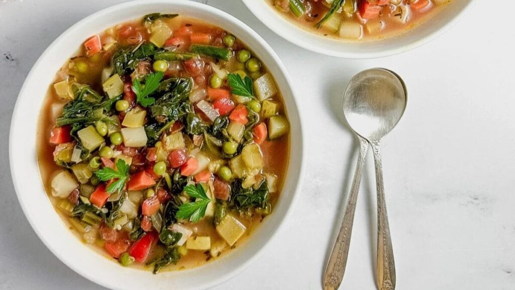 Traditional vegetable stew in a bowl next to a spoon.