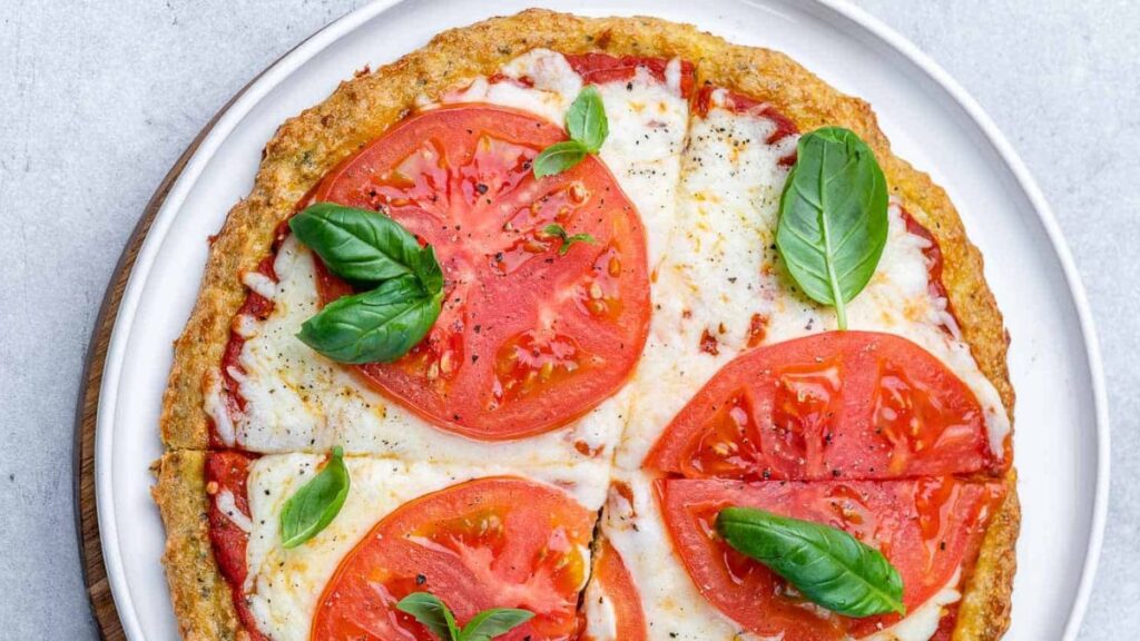 Pizza with tomatoes on a white plate.