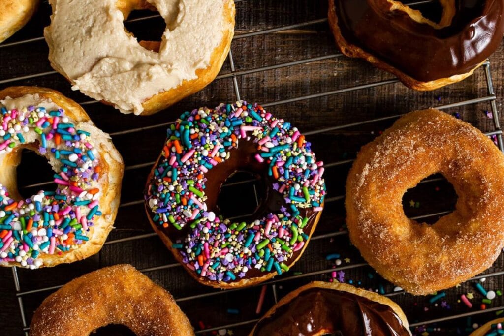 Selection of donuts with different toppings on a cooling rack.