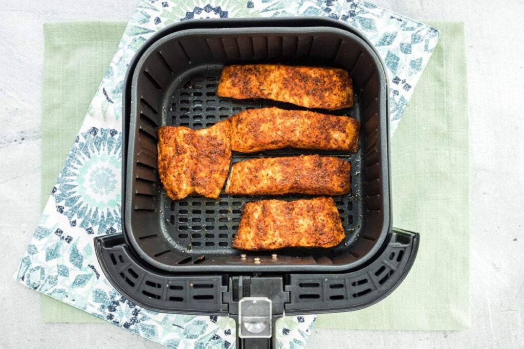Cooked air fryer salmon in the air fryer basket.