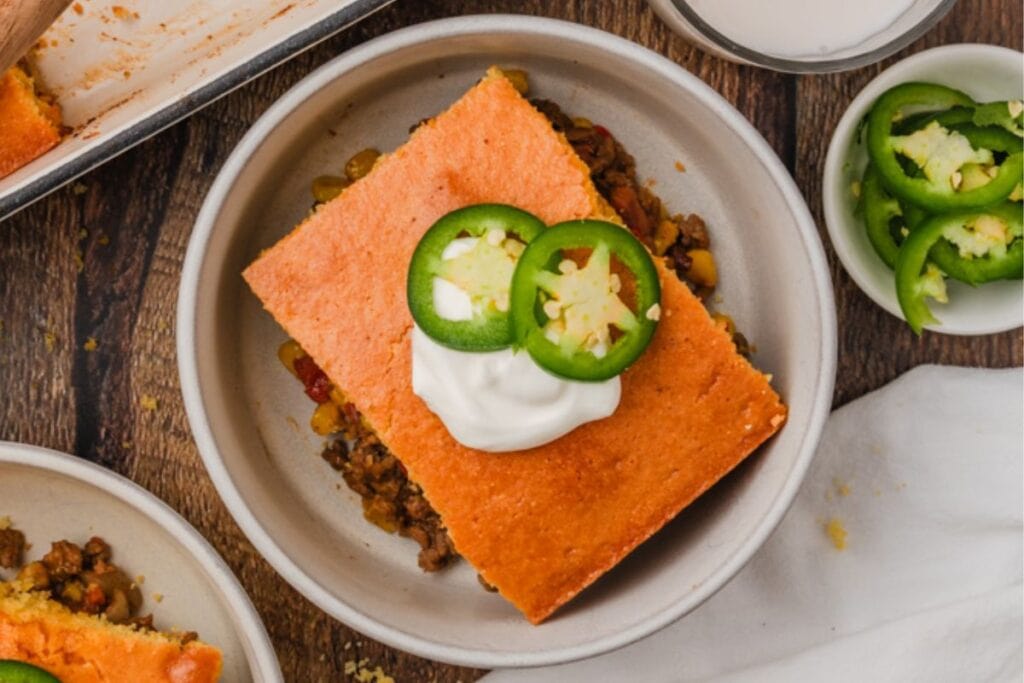 A slice of cornbread casserole with sliced green peppers on top.