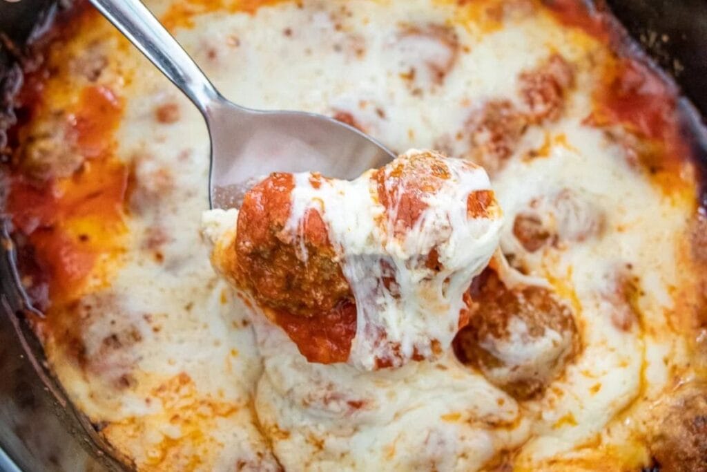 A spoonful of meatballs with cheese.