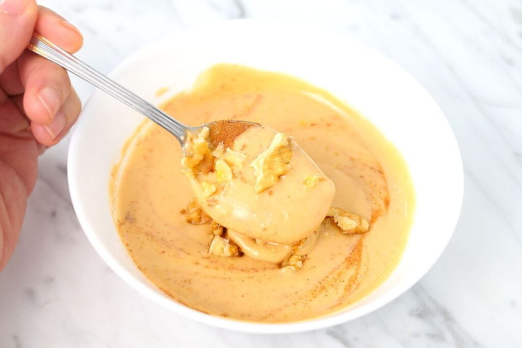 Peanut butter and yogurt bowl being eaten with a spoon.