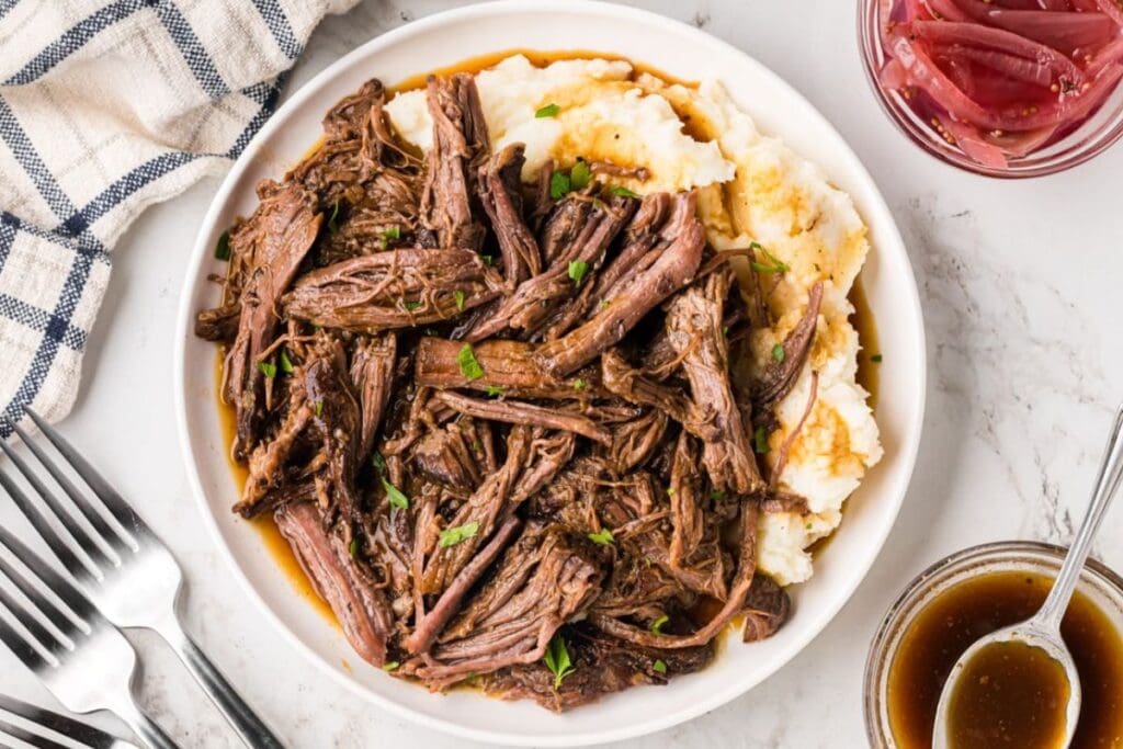 Pot roast with mashed potatoes on a plate.