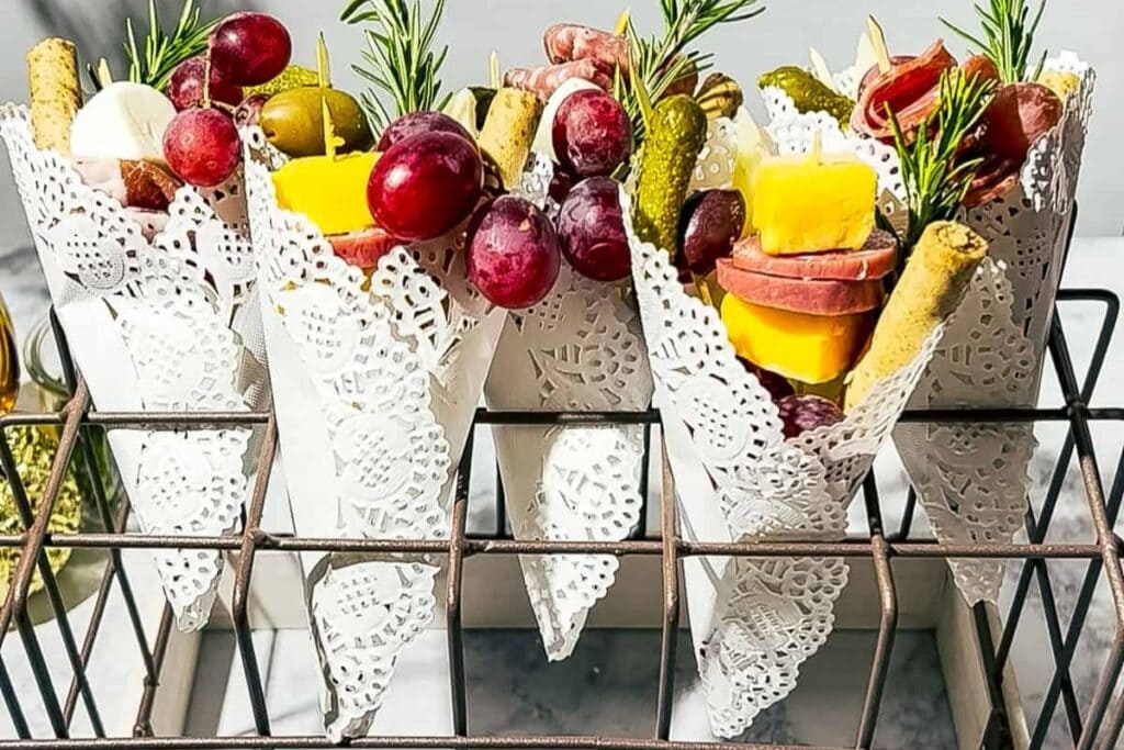 Easter charcuterie cones wrapped in white paper with charcuterie goodies.