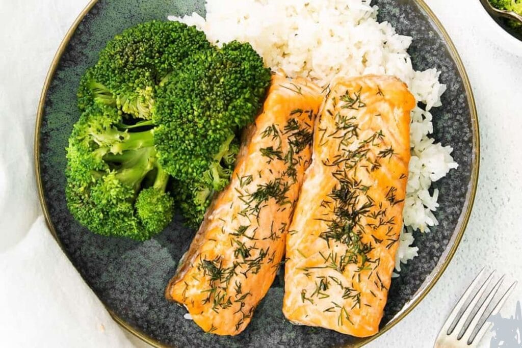 Salmon with rice and broccoli on a plate.