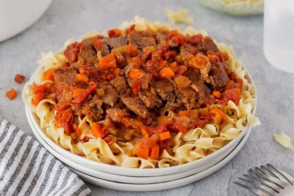 Pasta with swiss steak on top.