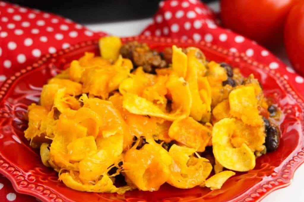 Frito taco pie on a red plate with a red polka dot napkin.