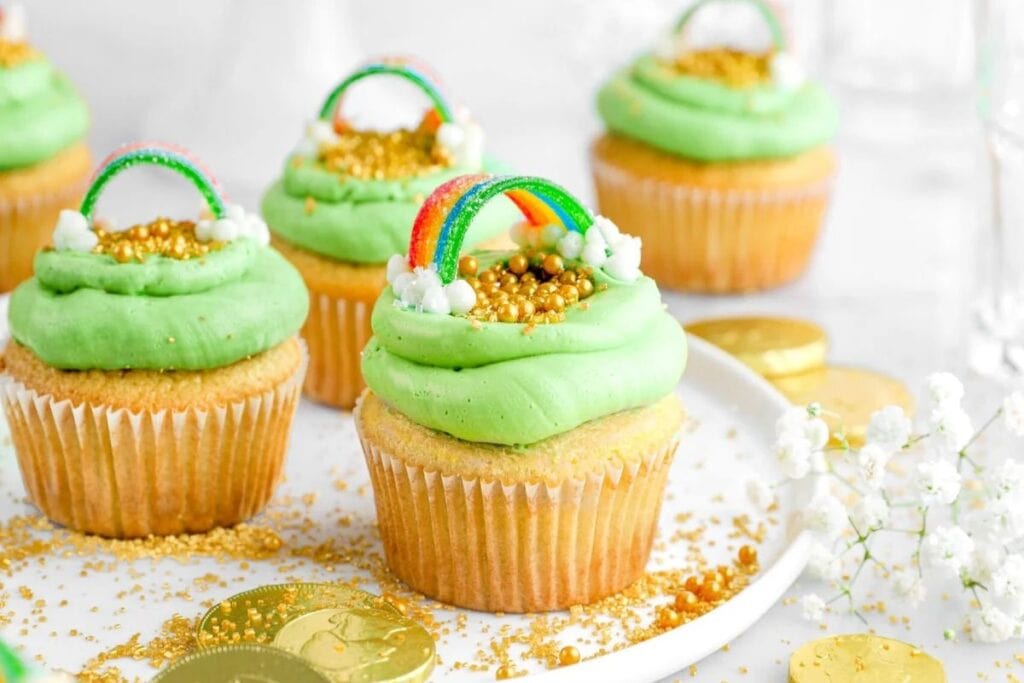 Vanilla cupcake with frosting that is green and candy rainbow.
