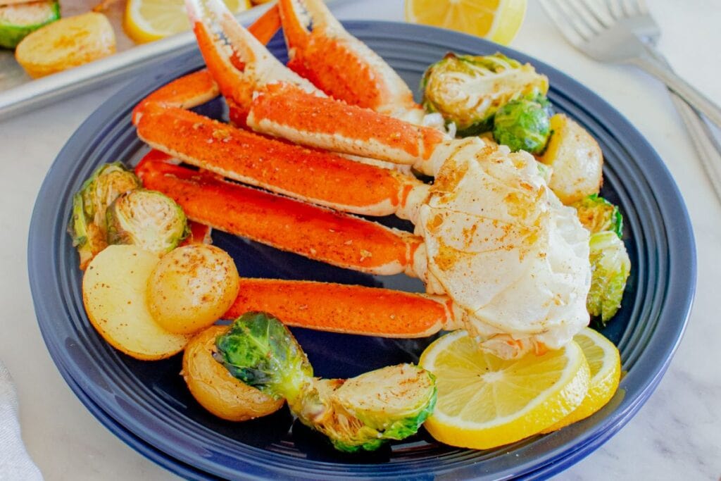 Crab legs with sliced lemons on a plate.