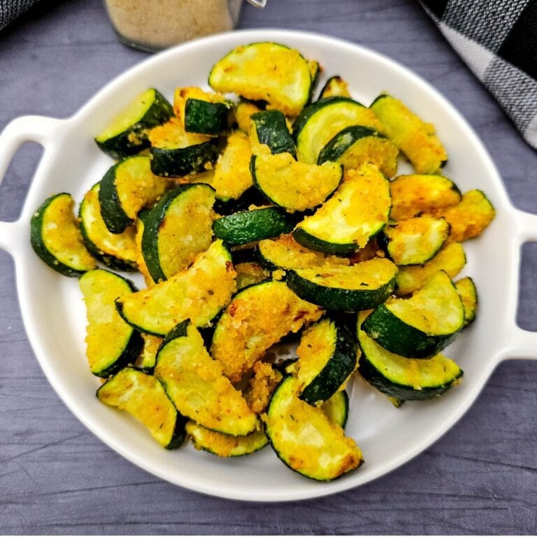 Air fried zuchini in a white bowl with a grey background.