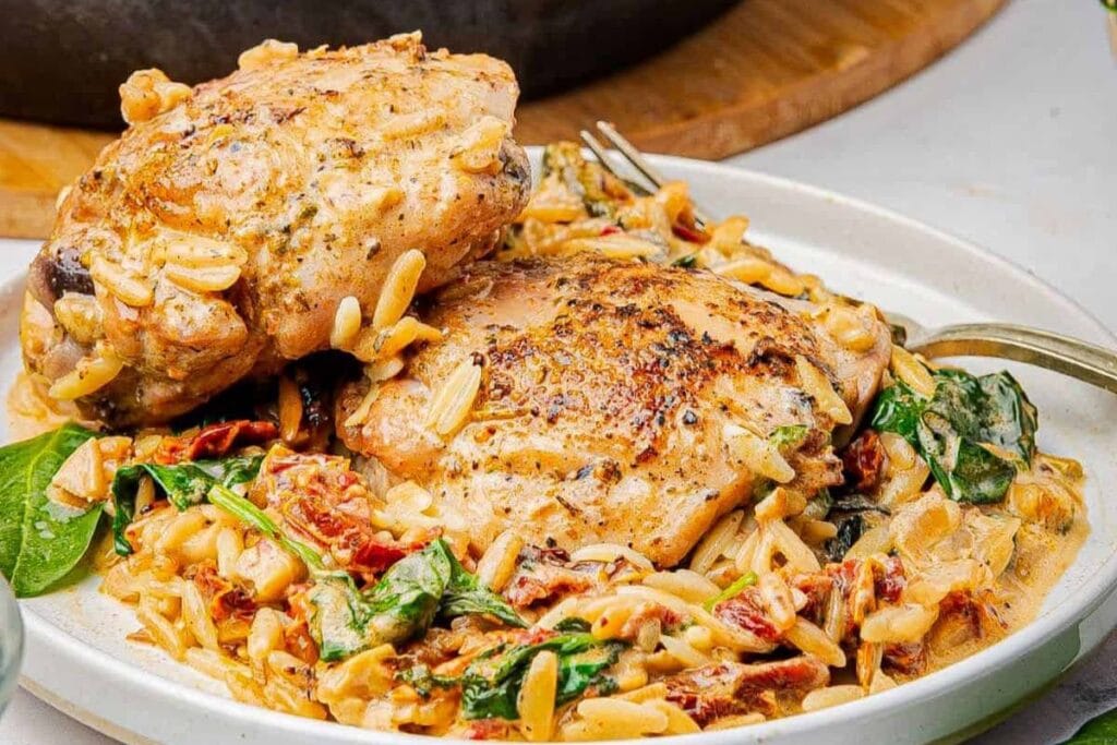 Baked chicken and orzo on a plate.