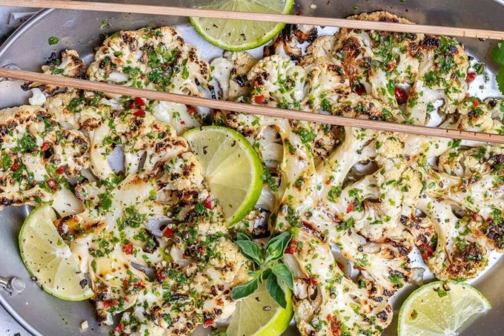 Grilled cauliflower with sliced limes.
