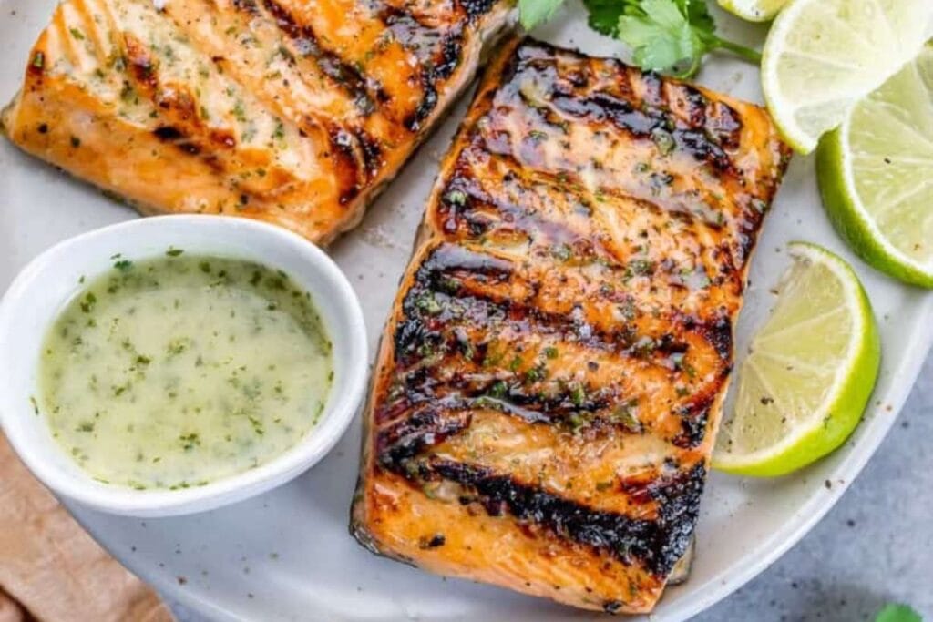 Grilled salmon with dip and sliced limes.