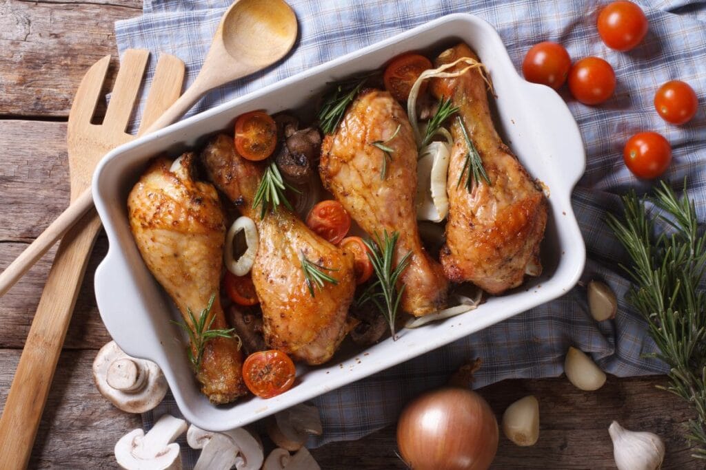 Chicken and veggies in a white serving dish with fresh herbs.