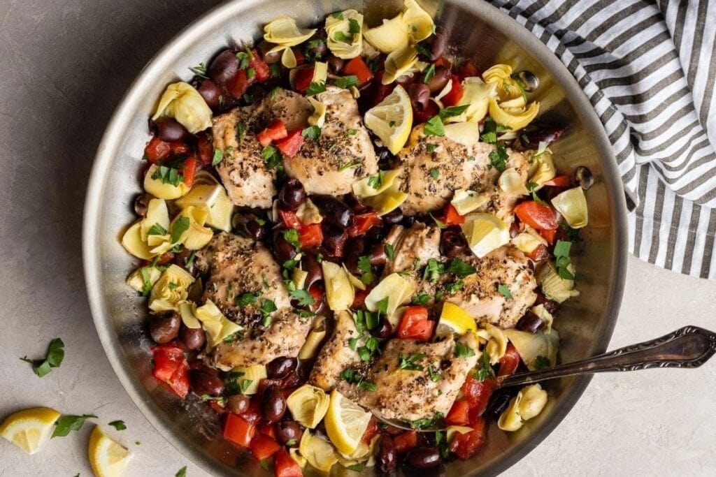 A bowl of chicken with olives.