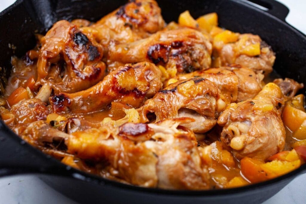 Skillet peach glazed chicken legs close up.