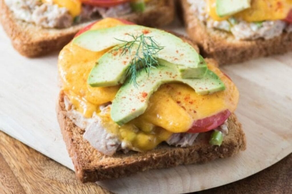 Tuna melt sandwich with sliced avocados.