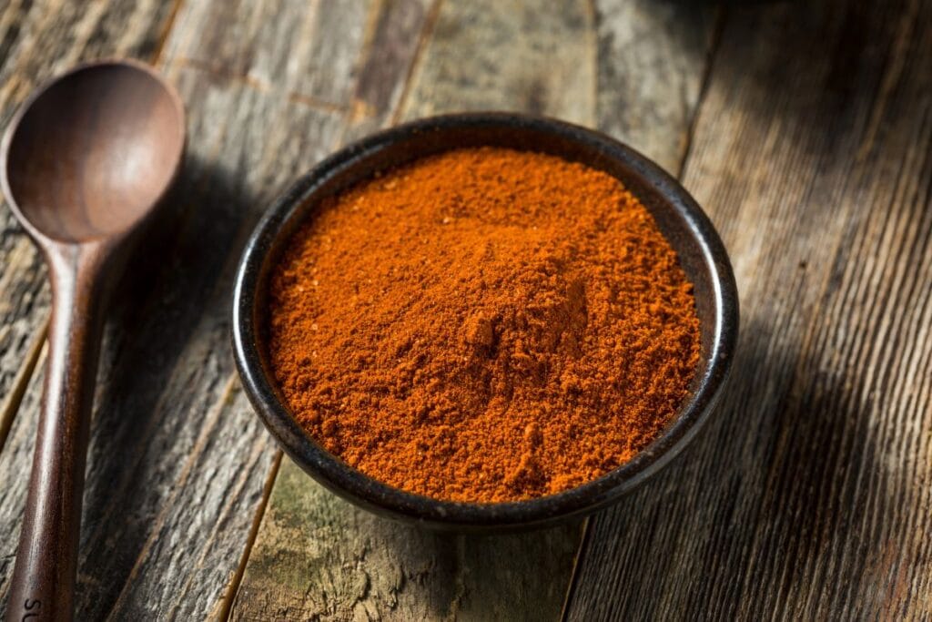 Dry seasoning in a black bowl on a wooden table.