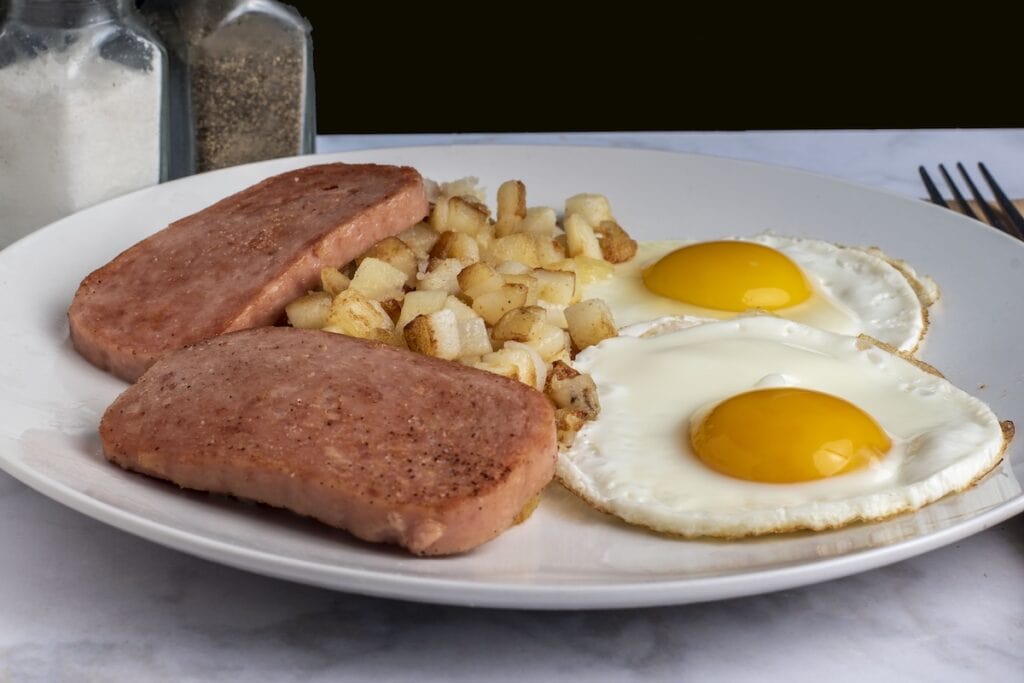 Sliced spam and sunny side up eggs on a plate.